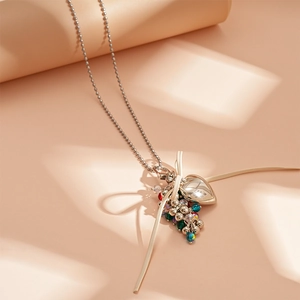 Detailed shot of metallic heart pendant with ribbon bow and colorful beads on a silver chain