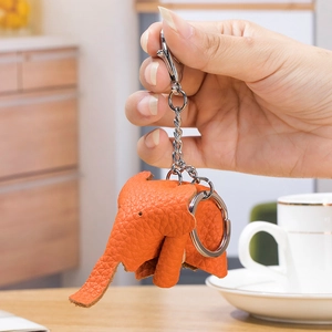 Orange genuine leather elephant keychain with lychee texture held in a hand