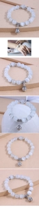 Detail of beaded bracelet with white opal-style stones and silver hollow bell charm