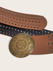 Detail of vintage round metal buckle with embossed patterns on studded PU leather belts