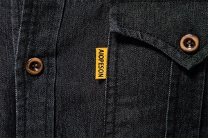 Detailed close-up of dark denim fabric texture with premium brown wooden buttons