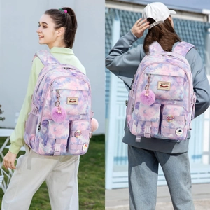 Close-up of purple tie-dye backpack with plush ball charm and LOVE decorative badges
