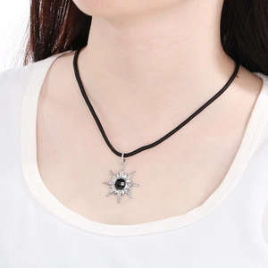 Détail du collier soleil en argent avec pierre noire porté au cou d'un mannequin
