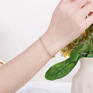 Elegant gold tennis bracelet with white zircons worn on wrist with floral accents