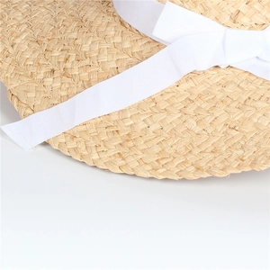 Close-up of natural raffia straw weaving texture and elegant white ribbon bow detail