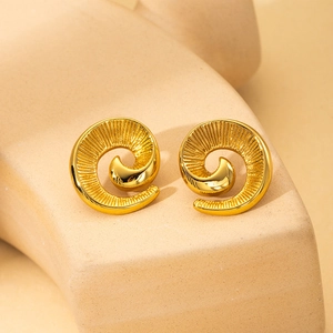 Macro shot of gold spiral textured earrings with vintage shell design on a matte surface