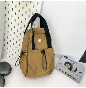 Detail of khaki nylon bag with adjustable drawstring closures and wide black shoulder strap