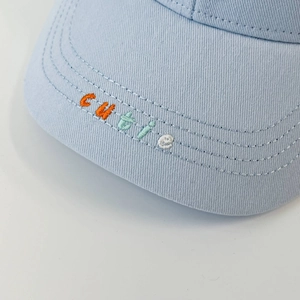 Detail of blue kids baseball cap featuring colorful cutie embroidery and neat stitching