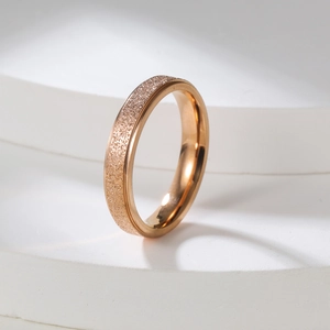 Detailed close-up of a 2mm matte rose gold ring with a sparkling sandblasted finish