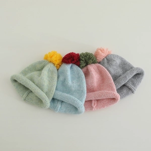 Colorful knit beanies with contrasting pom-poms for children in four trendy winter colors