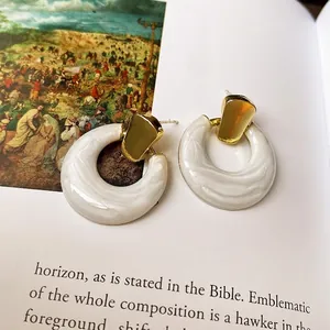 Elegant gold and white marble resin geometric drop earrings on artistic book background