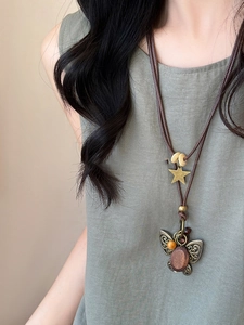 Detail of vintage butterfly pendant with wooden inlay on braided wax cord necklace