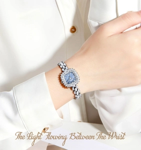 Gros plan d'une montre carrée en nacre bleue avec lunette diamants et bracelet floral