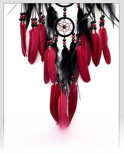 Détail d'un attrape-rêves bohème avec plumes rouge foncé et perles noires sur fond blanc
