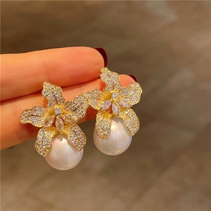 Sparkling lily flower stud earrings with gold metal petals and drop pearl detail