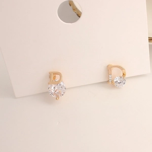 Detailed close-up of a gold geometric earring with a round zircon and micro-diamond D shape