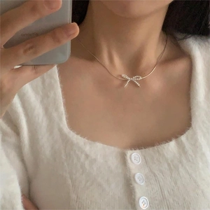 Mirror selfie showing bow pearl necklace on neck with gold chain detail