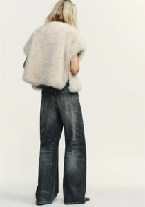 Rear view of faux fur mink vest in beige paired with vintage grey wide-leg jeans