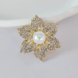 Exquisite flower brooch with a central pearl and sparkling crystal petals on gold metal