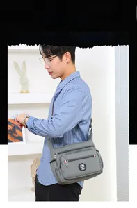 Close-up showing multiple zipper compartments on gray messenger bag for men