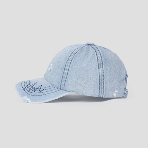 Detail of light blue washed denim cap with distressed holes and wave embroidery