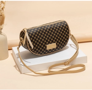 Close-up of a brown saddle bag with geometric patterns and beige leather trim detail