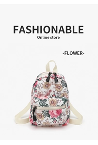 Detail view of cream floral canvas backpack featuring multiple functional zipper pockets