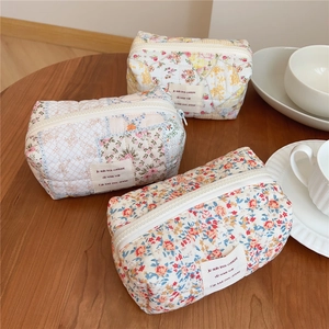 Detailed view of floral quilted cotton makeup bags with zippers on a wooden table