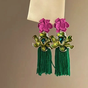 Detail of bohemian floral tassel earrings with magenta petals and green crystal leaves