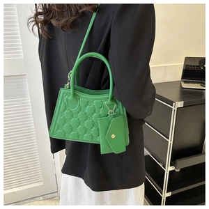 Detailed view of green quilted handbag with textured pattern and matching coin purse
