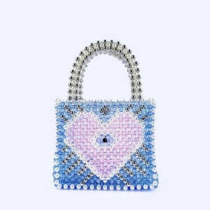 Detail of handmade beaded handbag featuring blue heart pattern and evil eye emblem