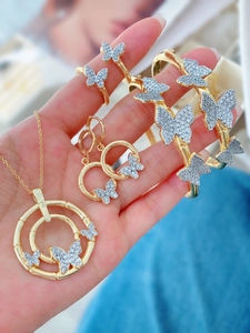 Macro shot of gold butterfly jewelry set featuring sparkling zircon stones and bamboo texture