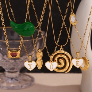 Detail of gold titanium necklaces with colorful enamel hearts and green chili pendants