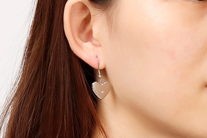 Macro shot of silver heart-shaped drop earrings in polished stainless steel for women