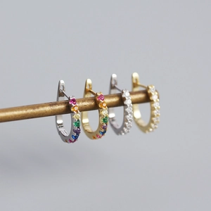 Detail of silver and gold U-shaped earrings set with colorful and clear gemstones