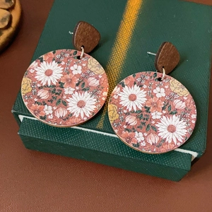 Detail view of round vintage earrings with floral patterns on a green jewelry box