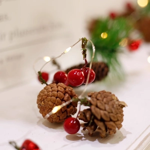 Christmas LED string lights with natural pine cones and red berries for festive home decor