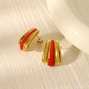 Close-up of vintage gold plated earrings with red enamel textured stripes and metal details