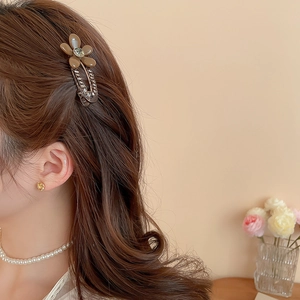 Detail of floral acrylic hair clip with rhinestone and metal chain on model's hair