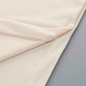 Close-up of beige knit fabric texture showing detailed weave on off-shoulder dress