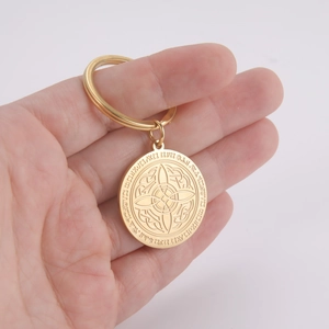 Golden stainless steel keychain with Celtic knot and rune pendant held by hand