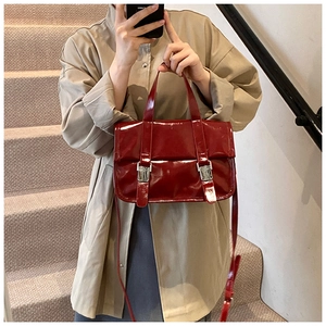 Detail of dark red patent leather handbag with dual silver metal buckle accents