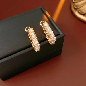 Gros plan de boucles d'oreilles dorées en U avec pavé de zircons blancs sur boîte à bijoux