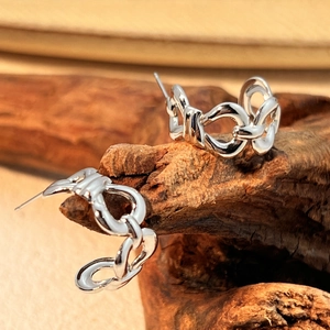 Silver chain-link C-shaped stainless steel earrings displayed on a rustic wood background