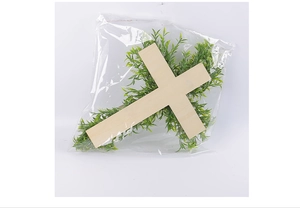 Detailed view of an Easter wooden cross wreath with green artificial leaves in clear packaging