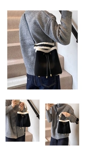 Detail of black suede bucket bag with white faux fur trim and gold drawstring hardware