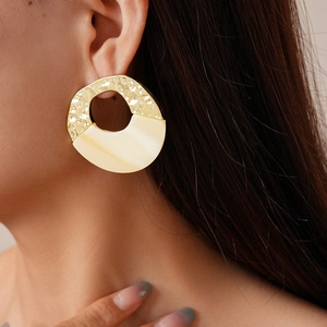 Close-up of a model wearing two-tone acrylic and gold metal irregular round earrings