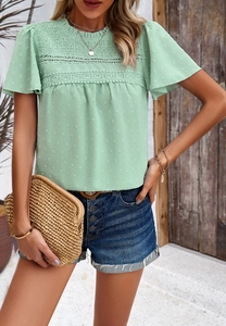 Detail of green short sleeve top with 3D polka dot fabric and delicate lace trim