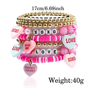 Detail of pink LOVE letter beads and heart pendants on multi-layered beaded bracelets