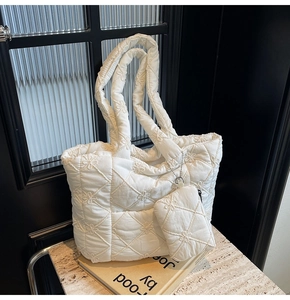 Detail of white quilted tote bag featuring floral embroidery and matching small pouch